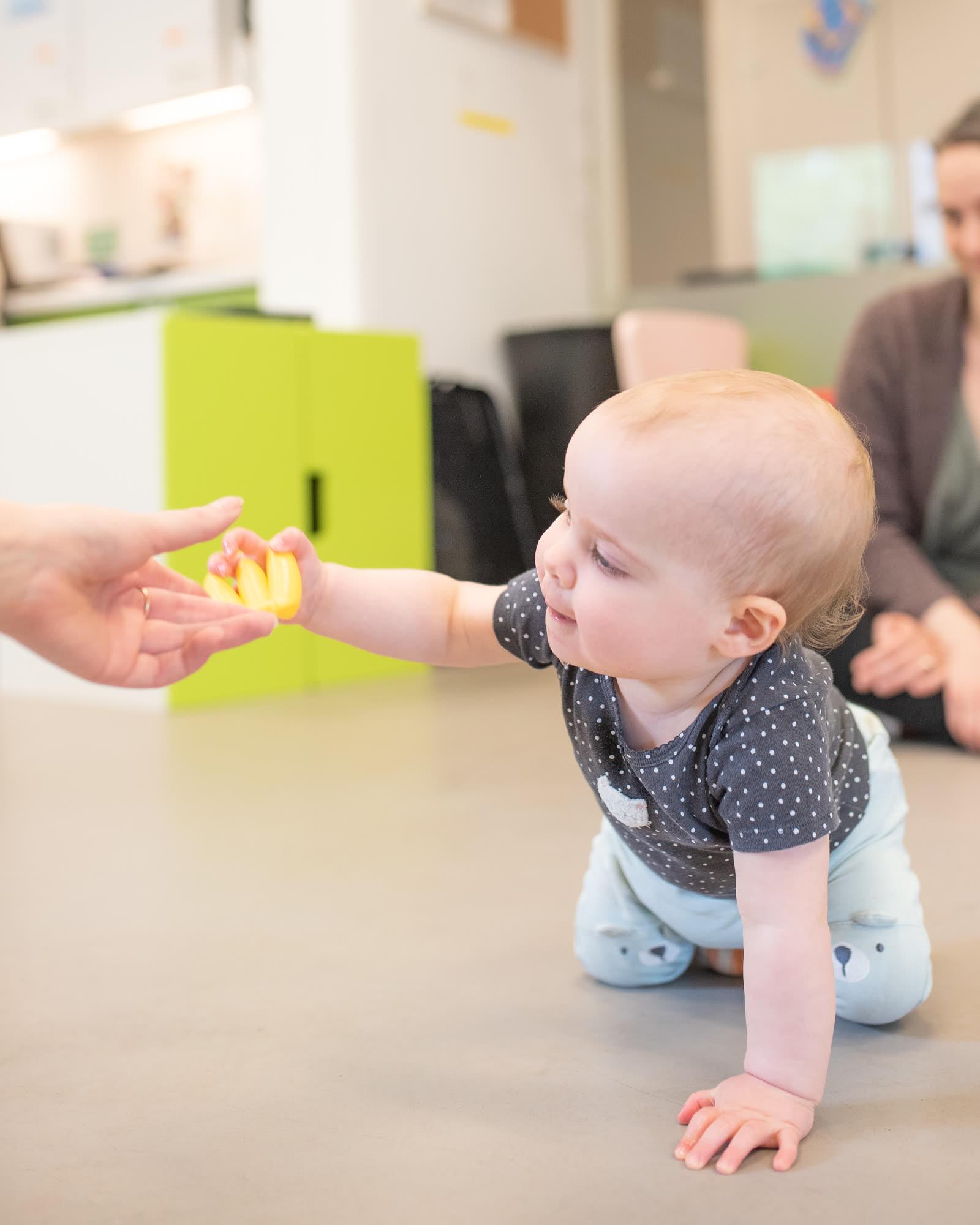 A toddler playing with a letter puzzle toy on a play mat